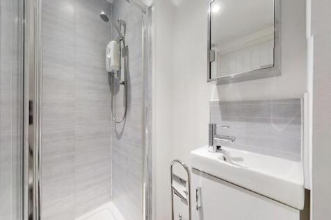 A modern bathroom suite featuring a sleek walk-...