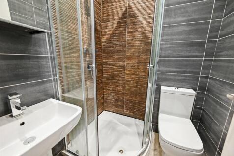 A modern bathroom suite featuring a glass-enclo...
