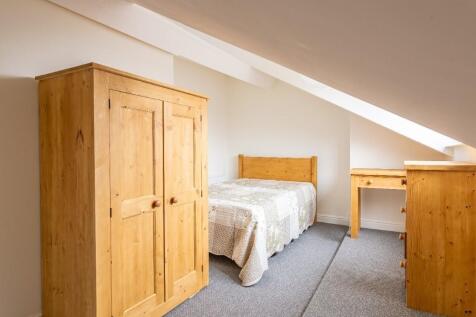 Cozy attic bedroom with sloped ceilings, featur...