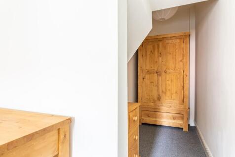 A tidy and narrow hallway featuring wooden furn...