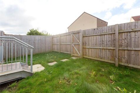 A private garden enclosed by wooden fencing wit...