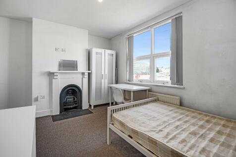 Bright single bedroom featuring a large window ...
