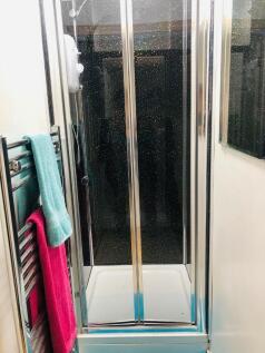 Compact bathroom featuring a glass-enclosed sho...