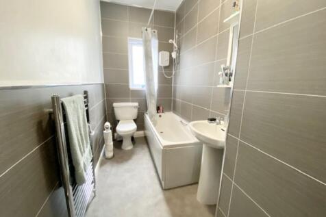 A modern, clean bathroom suite featuring a bath...