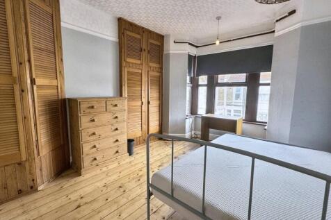 Bright double bedroom featuring natural wood fl...