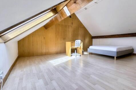 Bright attic bedroom with sloped ceiling and wo...