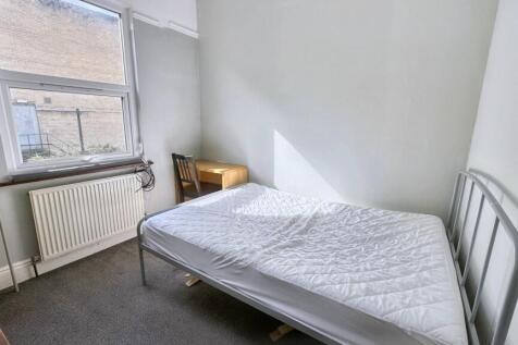 A simple, clean bedroom with a metal bed frame,...