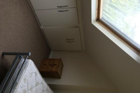 A small single bedroom featuring a large skylig...