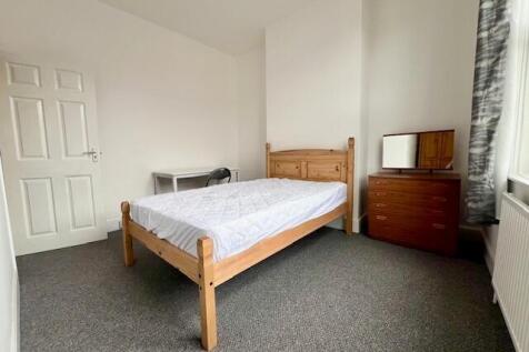 Bright double bedroom featuring a wooden bed fr...