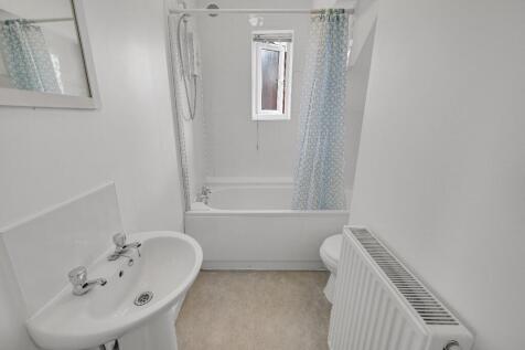 Bright and clean bathroom featuring a bath with...
