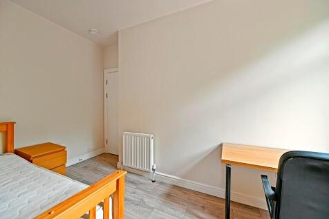 A neat and simple room featuring a wooden bed f...