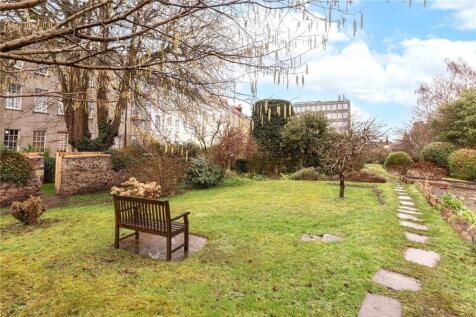 A well-maintained garden with a wooden bench, a...
