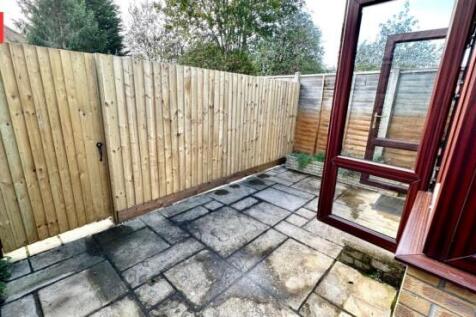 A private, paved garden area enclosed by a wood...