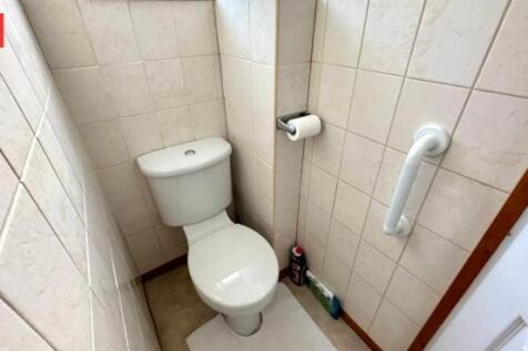 Compact and clean single toilet with tiled wall...