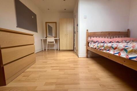 A neat and tidy bedroom with wooden flooring, f...
