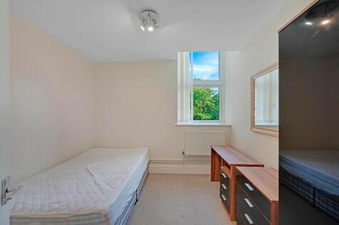A bright single bedroom featuring a large windo...