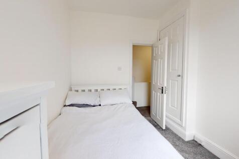 A bright and clean bedroom with white walls and...