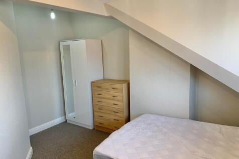 A tidy single bedroom featuring a neatly made b...