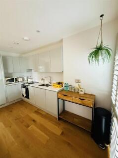A modern, bright kitchen featuring sleek white ...