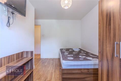 A tidy single bedroom featuring a wooden bed fr...