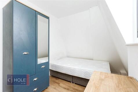 Cozy single bedroom featuring a neat wooden des...