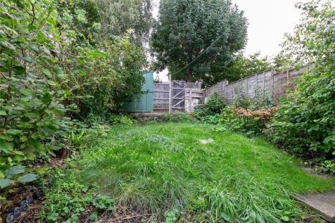 A lush, green garden space bordered by wooden f...