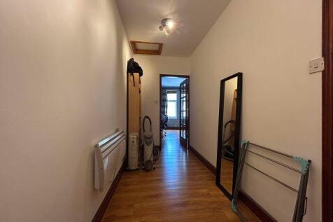 A clean and tidy hallway with wooden flooring a...
