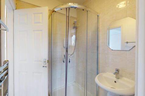 A clean, modern bathroom featuring a glass-encl...