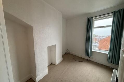 A cozy single bedroom with a large window drape...