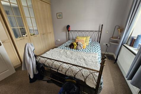 A cozy single bedroom featuring a neatly made b...