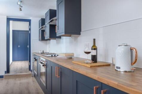 A modern kitchen featuring sleek dark cabinetry...