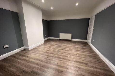 A spacious, modern living room with sleek wood-...