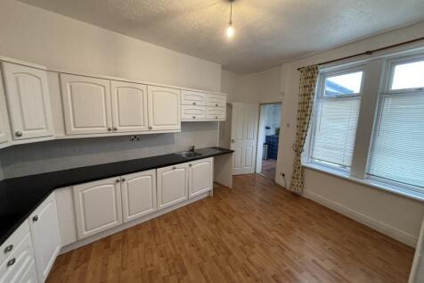 A spacious, well-lit kitchen with ample white c...
