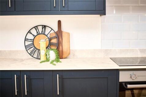 Modern kitchen featuring sleek navy cabinetry, ...