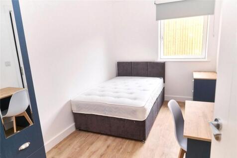 A neat and well-lit small bedroom with a comfor...