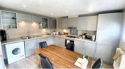 A bright and modern kitchen featuring white cab...