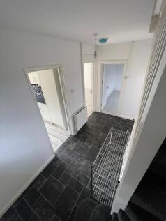 A clean and tidy hallway featuring dark tiled f...