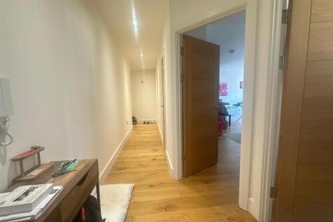 Bright and clean hallway with wooden flooring a...