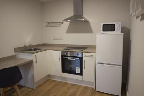 A modern compact kitchen featuring clean white ...