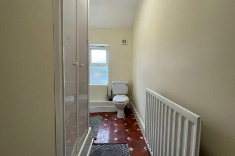A clean and simple single toilet room with a wh...