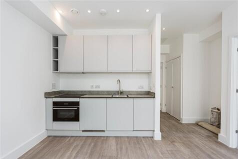 A modern, compact kitchen featuring white cabin...