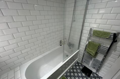 Modern bathroom featuring a clean white tiled b...
