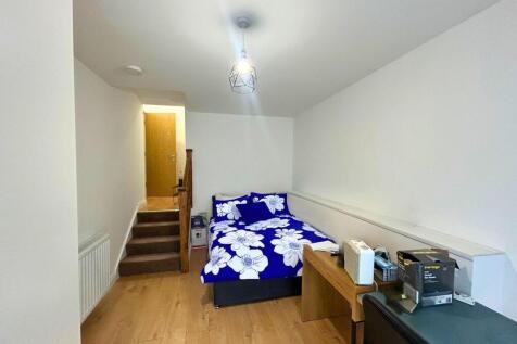 A neat single bedroom featuring a cozy bed with...