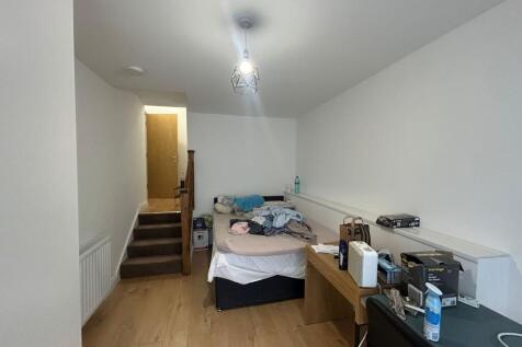 A compact room featuring a bed and desk area, w...