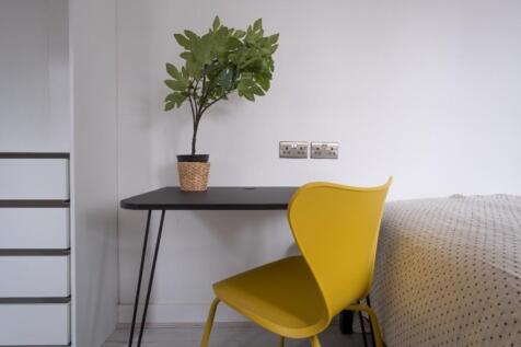 A cozy double bedroom featuring a stylish desk ...