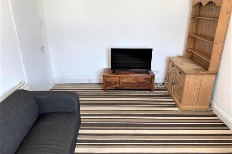 A cozy living room featuring a dark sofa, strip...