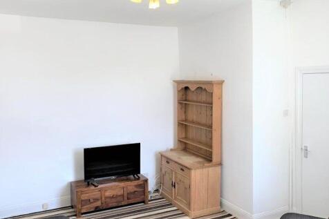 A simple living room featuring a TV on a wooden...