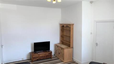 A simple living room featuring a wooden TV stan...