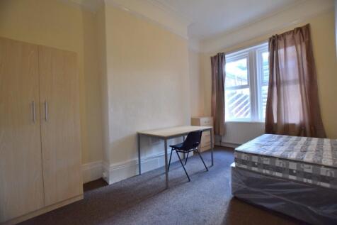 A cozy single bedroom featuring a large window ...