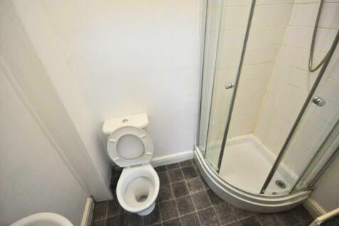 A compact bathroom featuring a corner shower un...